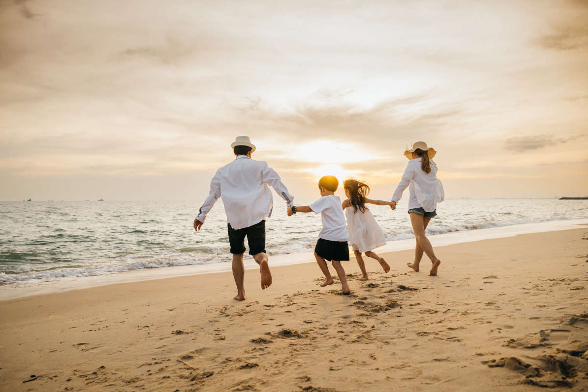 Asian family happiness at beach parents and daughters play together. Back view captures joyful moments of little girls bonding with their mother and father pretending to fly on carefree weekend. Why Choose Us?